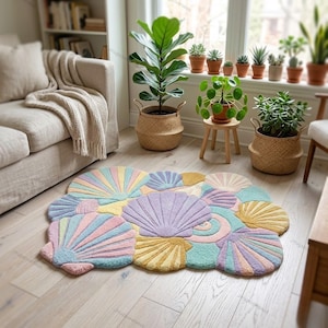 Könnte beinhalten: Ein getufteter Teppich in Form einer Ansammlung von Muscheln in Pastelltönen wie Rosa, Blau, Gelb und Lavendel. Der Teppich zeigt verschiedene Muschel-Designs mit strukturierten, erhabenen Mustern und bildet einen weichen Bodenbelag für den Raum.