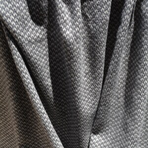 a close-up view of a fabric with a gray and white checkered pattern, with the fabric appearing crumpled and folded.
