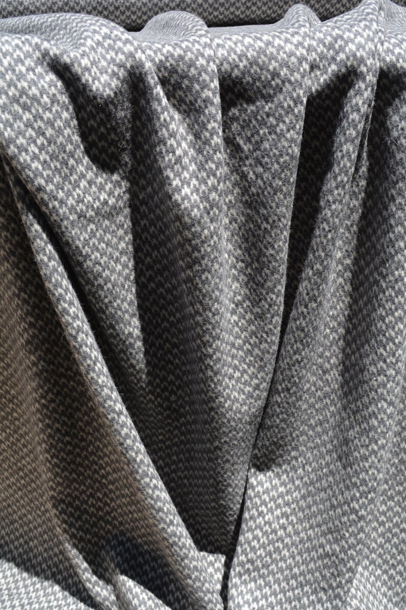 a close-up view of a fabric with a gray and white checkered pattern, with the fabric appearing crumpled and folded.