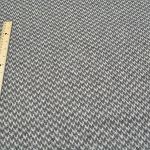 a close-up view of a grey and white checkered pattern on a fabric surface, with a ruler placed next to it for scale.