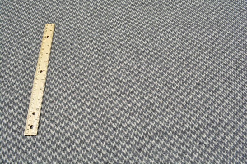 a close-up view of a grey and white checkered pattern on a fabric surface, with a ruler placed next to it for scale.