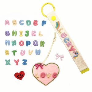 May include: A selection of colourful embroidered patches and accessories. Includes alphabet letters, a heart with "LOVE" text, a "LUCKY" keychain with a rainbow and unicorn, and a red heart with a smiling face.