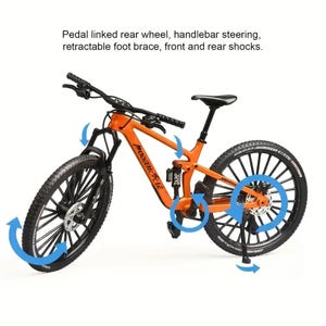 Op de afbeelding: Een oranje mountainbike met zwarte banden en onderdelen. De fiets heeft voor- en achterschokdempers, stuurstangbesturing en een intrekbare voetsteun. De tekst op de fiets luidt "MODEIBICYCLE". De afbeelding bevat ook de tekst "Pedal linked rear wheel, handlebar steering, retractable foot brace, front and rear shocks."