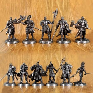 以下が含まれることがあります： さまざまなポーズで、斧、槍、剣などの武器を持っているミニチュアの金属製の騎士のフィギュアのコレクション。 フィギュアは鎧とヘルメットで詳細に描かれており、木製の表面に表示されています。