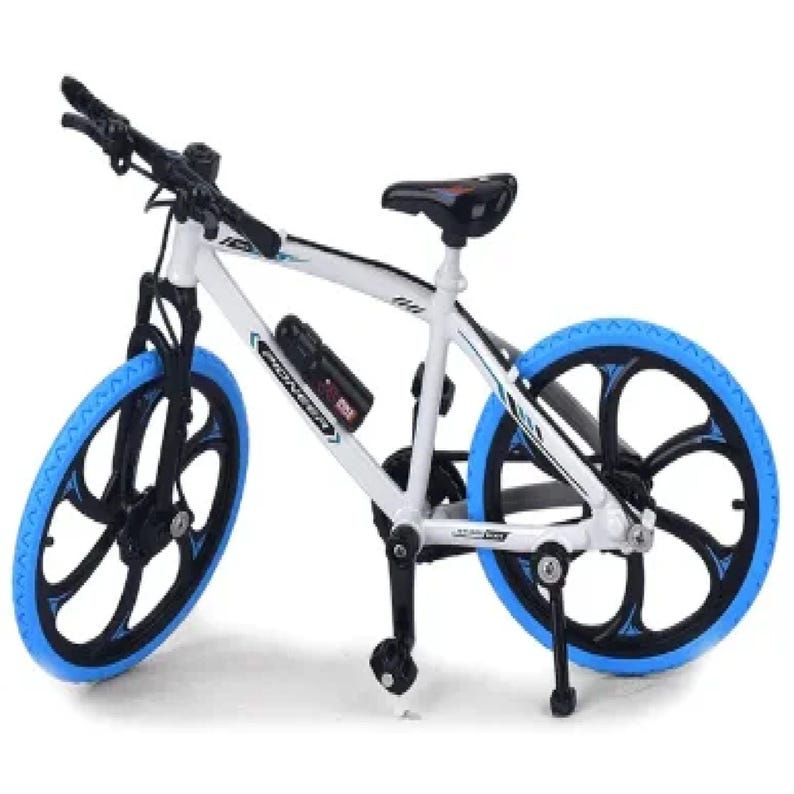 Op de afbeelding: Een wit en zwarte miniatuurfiets met blauwe banden en accenten. De fiets heeft een zwart zadel, stuur en een bidonhouder. De wielen hebben een uniek zwart en blauw spaakontwerp.