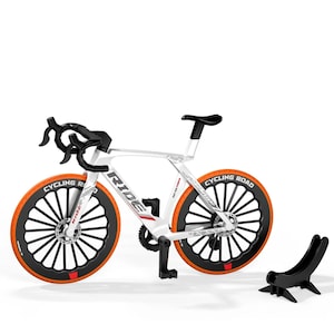May include: A white and black road bicycle model with orange tires and the text "CYCLING ROAD". The bicycle has black handlebars and a black seat. A black stand is next to the bicycle.
