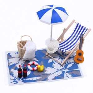 May include: Miniature beach scene with a blue and white striped beach chair, a blue and white umbrella, and a blue beach towel with a palm tree design. Includes a basket, towel, guitar, and toy bottles.
