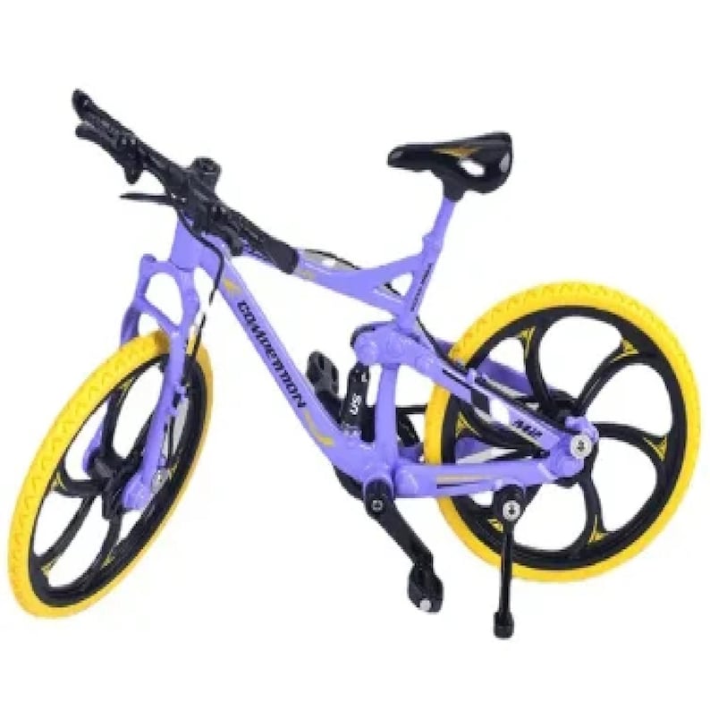 Op de afbeelding: Een paarse en zwarte mountainbike met gele banden. De fiets heeft het woord "Competition" op het frame gedrukt. De wielen hebben een zwart en geel ontwerp. Het zadel is zwart en geel.