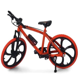 Op de afbeelding: Een miniatuurfiets in oranje en zwart. De fiets heeft zwarte banden met oranje velgen en een zwart zadel. Het frame is oranje met zwarte accenten. Met bidonhouder.