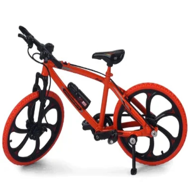 Op de afbeelding: Een miniatuurfiets in oranje en zwart. De fiets heeft zwarte banden met oranje velgen en een zwart zadel. Het frame is oranje met zwarte accenten. Met bidonhouder.