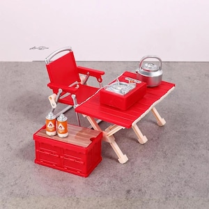May include: Miniature camping set with a red folding chair, table, and storage box. Includes a red stove, a silver kettle, and two gas canisters. The table and storage box have a wood-grain top.