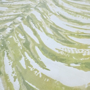 May include: A close-up of a fabric with a watercolor design. The pattern features flowing, curved lines in shades of green and olive against a white background. The design resembles stylized leaves or brushstrokes, creating a natural, organic aesthetic.