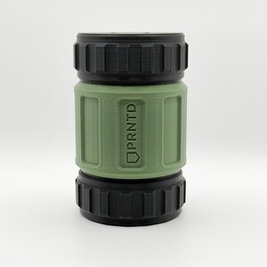May include: A cylindrical object with a black top and bottom and a green center section. The center section has the word "PRNTD" printed vertically. The object has a textured, ridged design.