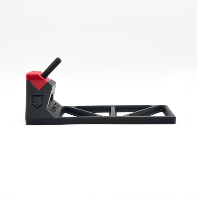 Pode incluir: Um suporte de pl&aacute;stico preto e vermelho com uma base horizontal com padr&atilde;o de recortes triangulares e um bra&ccedil;o de suporte vertical. A palavra PRNTO est&aacute; gravada na lateral da estrutura preta e um pequeno &iacute;cone de escudo sob a parte superior vermelha.