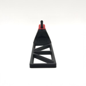 Pode incluir: Um suporte de pl&aacute;stico preto com uma base triangular de estrutura aberta e uma pe&ccedil;a de destaque vermelha no topo. Um pequeno pino preto estende-se verticalmente a partir do centro da sec&ccedil;&atilde;o vermelha. A palavra PRNTP est&aacute; gravada na frente.