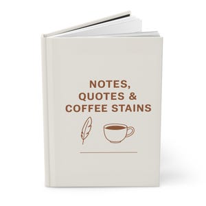 Puede incluir: Un diario de color crema con el texto "NOTES, QUOTES & COFFEE STAINS" en marrón. La portada presenta una pluma y una ilustración de taza de café. El diario está abierto, revelando páginas blancas rayadas.