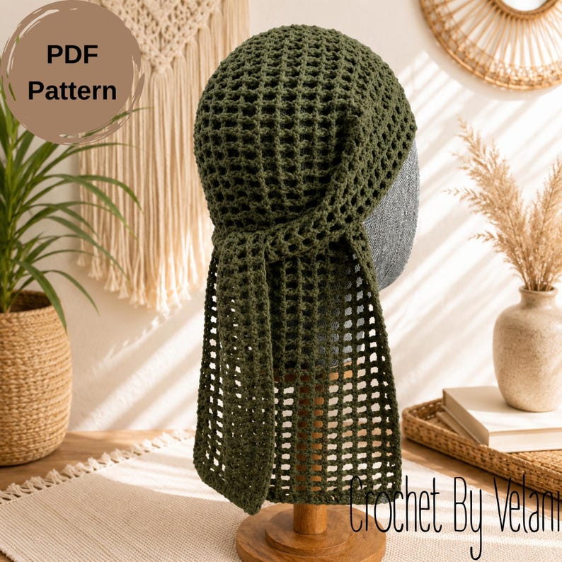 May include: An olive green crochet head covering featuring a grid-like openwork pattern. The design includes a rounded cap section with two long, rectangular fabric tails hanging down from the back. The text PDF Pattern is visible in the corner.