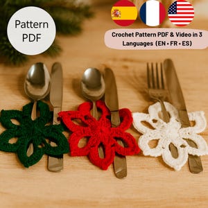 Op de afbeelding: Een close-up van drie besteksets, elk met een gehaakte bloemvormige houder in groen, rood en wit. De afbeelding bevat de tekst "Pattern PDF" en "Crochet Pattern PDF & Video in 3 Languages (EN • FR • ES)".