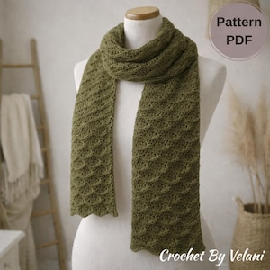 May include: Olive green crochet scarf displayed on a mannequin. The scarf has a textured, wavy pattern and a scalloped edge. The text "Pattern PDF" is in a circle on the right. The text "Crochet By Velani" is at the bottom.