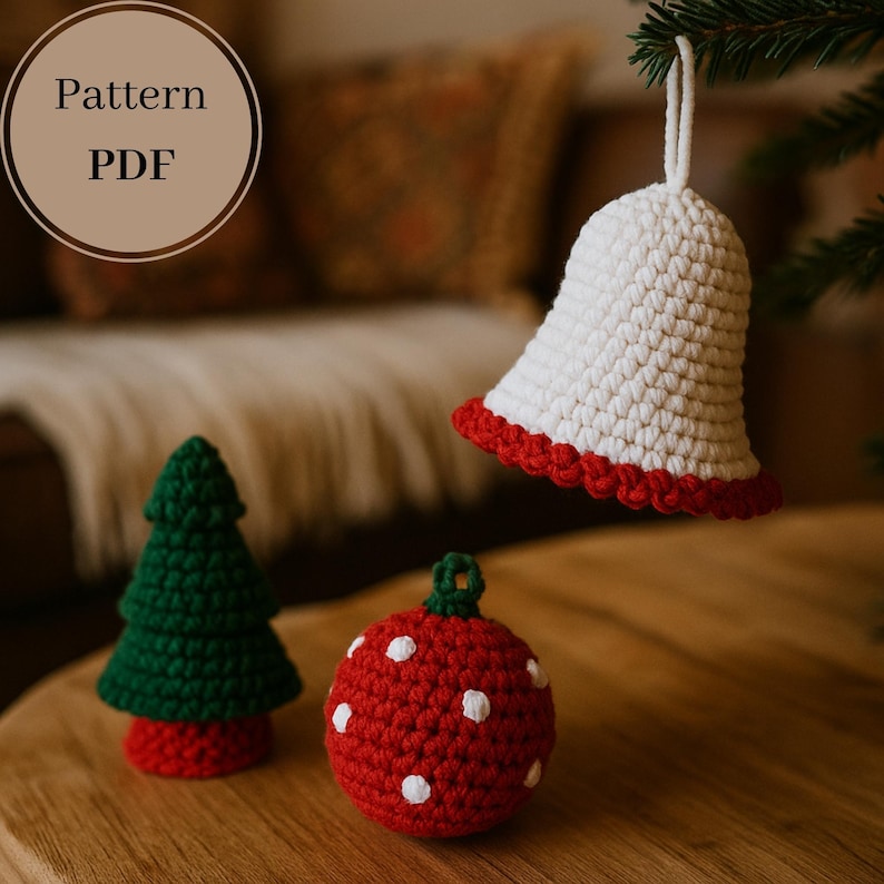Op de afbeelding: Handgemaakte gehaakte kerstversieringen. De afbeelding toont een witte bel met een rode rand, een groene kerstboom en een rode bal met witte stippen. De afbeelding bevat de tekst "Pattern PDF".