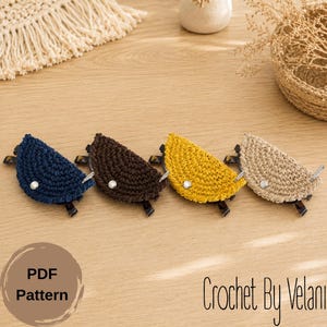 May include: Four crochet eyeglass holders in navy blue, brown, yellow, and beige. Each holder has a white button and a dark frame. The text "PDF Pattern" is in a circle, and "Crochet By Velani" is written in cursive.