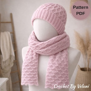 May include: A light pink knitted hat and scarf set displayed on a mannequin. The hat is a beanie style with a textured pattern, and the scarf has a matching design. The text "Pattern PDF" is visible. The text "Crochet By Velani" is also visible.