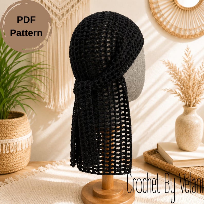 May include: A black crochet head covering featuring a grid-like openwork pattern. The design includes a fitted cap section with a long, rectangular tail piece that hangs down from the back. The text PDF Pattern is visible in the upper left corner.