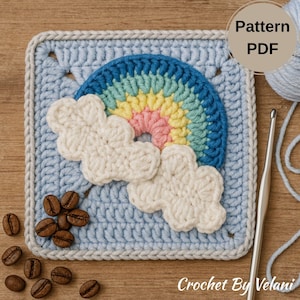 Op de afbeelding: Een gehaakte vierkant met een regenboog en twee witte wolken. De regenboog heeft blauwe, groene, gele en roze bogen. De vierkant is lichtblauw met een grijze rand. De tekst "Pattern PDF" is zichtbaar.