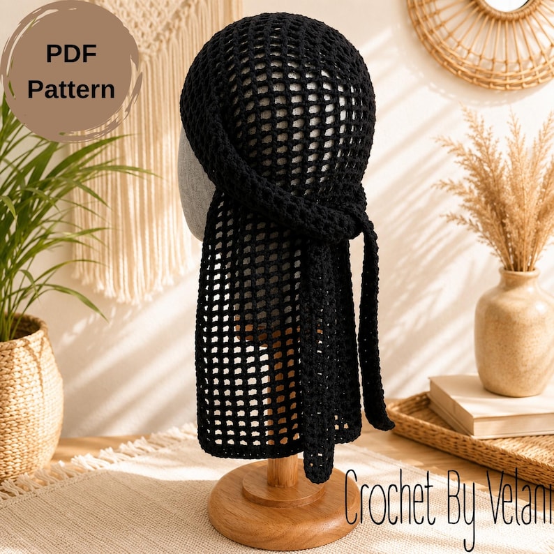 May include: A black crochet headscarf featuring an open grid pattern and long ties at the back. The headscarf is displayed on a mannequin head. The image includes the text PDF Pattern and Crochet By Velani in the corners of the frame.