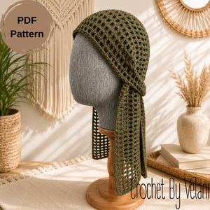 May include: An olive green crochet headscarf featuring an open-work grid pattern with two long, rectangular ties hanging down from the sides. The item is displayed on a gray mannequin head. The image includes the text PDF Pattern.