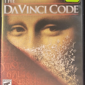 May include: PlayStation 2 video game case for "The Da Vinci Code." The cover features a portion of the Mona Lisa painting with overlaid text and numbers. The game is rated "T" for Teen by the ESRB.
