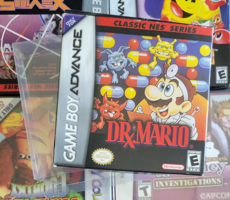 Op de afbeelding: Game Boy Advance game case voor "Dr. Mario" met het personage in een doktersjas, omringd door cartoonvirussen en pillen. De case zit in een beschermende plastic hoes, met het "Classic NES Series" logo zichtbaar.