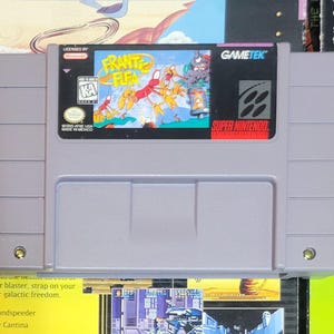 May include: A Super Nintendo video game cartridge for the game "Franky Fifi". The cartridge is gray with a colorful label featuring cartoon characters. The label includes the "Super Nintendo" logo and the Gametek logo.
