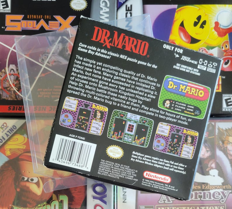 Op de afbeelding: Een Dr. Mario Game Boy Advance videospeldoos. De zwarte doos heeft kleurrijke graphics en tekst, waaronder de speltitel en screenshots. Het zit in een beschermende plastic hoes, met andere speldozen op de achtergrond.