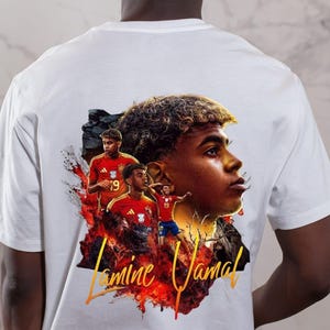May include: White t-shirt with a graphic of a soccer player, featuring the name "Lamine Yamal" in orange script. The design includes images of the player in a red and yellow uniform, set against a fiery background.