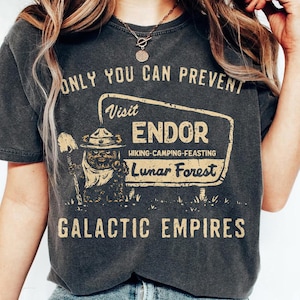 May include: Charcoal grey t-shirt with a retro graphic. The design includes the text "ONLY YOU CAN PREVENT" above a sign that reads "Visit ENDOR Lunar Forest." Below the sign, it says "GALACTIC EMPIRES."