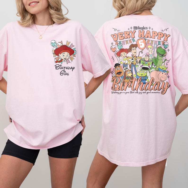 May include: Pink t-shirts with cartoon graphics. One shirt features a cartoon character and the text "Birthday Girl." The other shirt has a "Very Happy Birthday" design with cartoon characters and the number 5. The shirts are a light pink color.