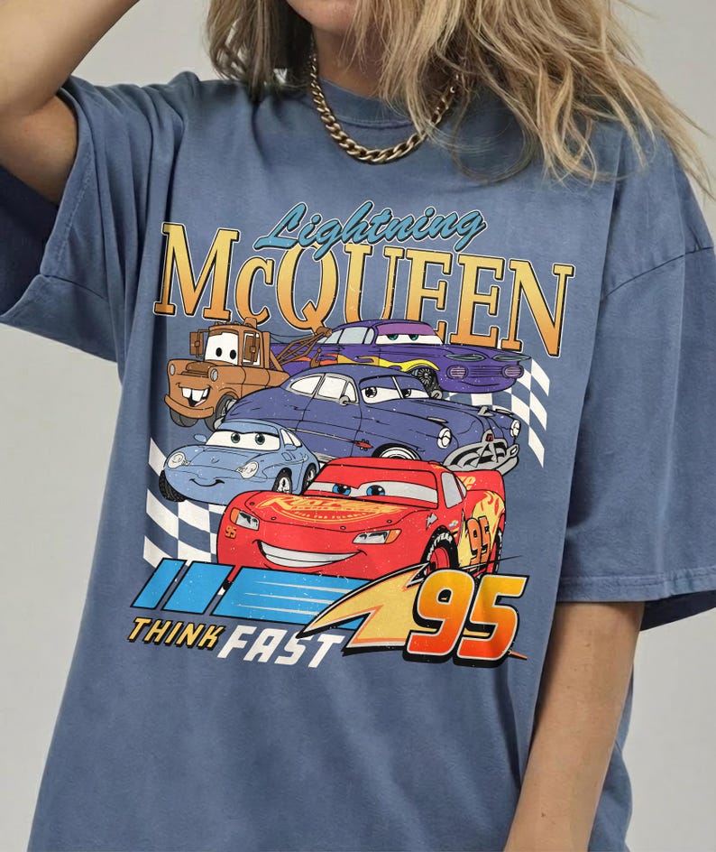 Puede incluir: Camiseta azul con un dise&ntilde;o de Rayo McQueen y otros personajes de Cars. El dise&ntilde;o incluye el texto "Lightning McQueen", "Think Fast" y el n&uacute;mero "95". La camiseta tiene un aspecto vintage y desgastado.