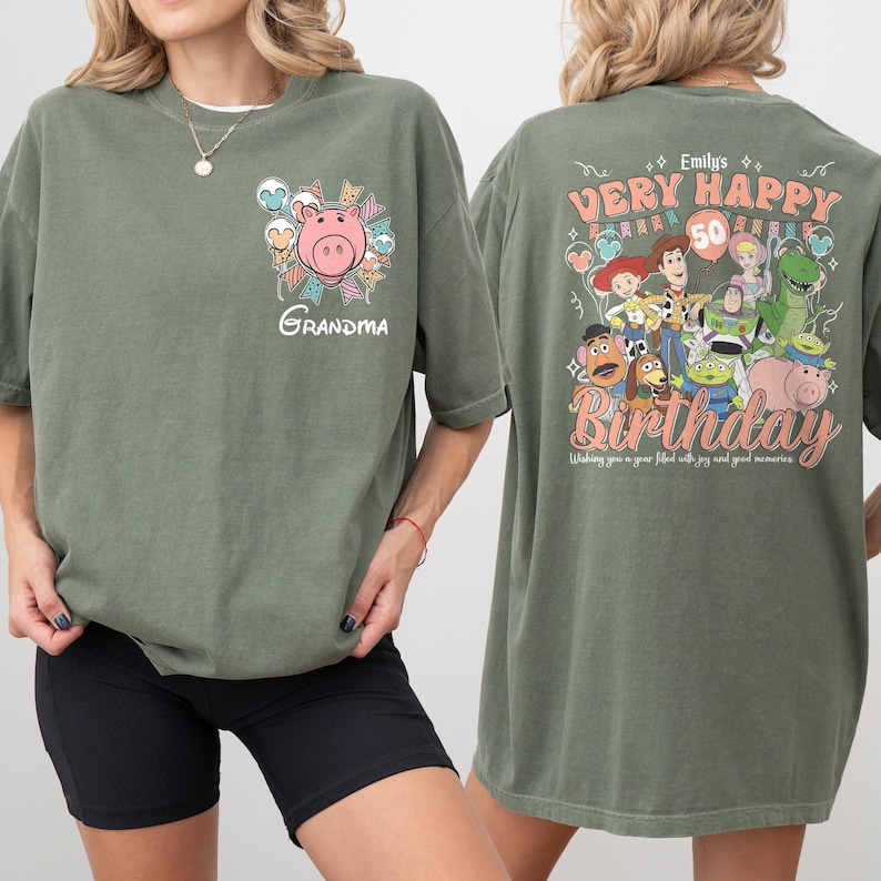May include: Olive green t-shirt with a graphic of a pink pig and the word "Grandma" on the front. The back features a "Very Happy Birthday" design with cartoon characters and the number 50. The text "Wishing you a year filled with joy and good memories" is also included.