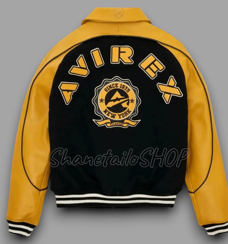 May include: A black and yellow varsity jacket with the word "AVIREX" across the back. The jacket features a patch that says "Since 1975 New York Classic". The jacket has a white and black striped hem and cuffs.