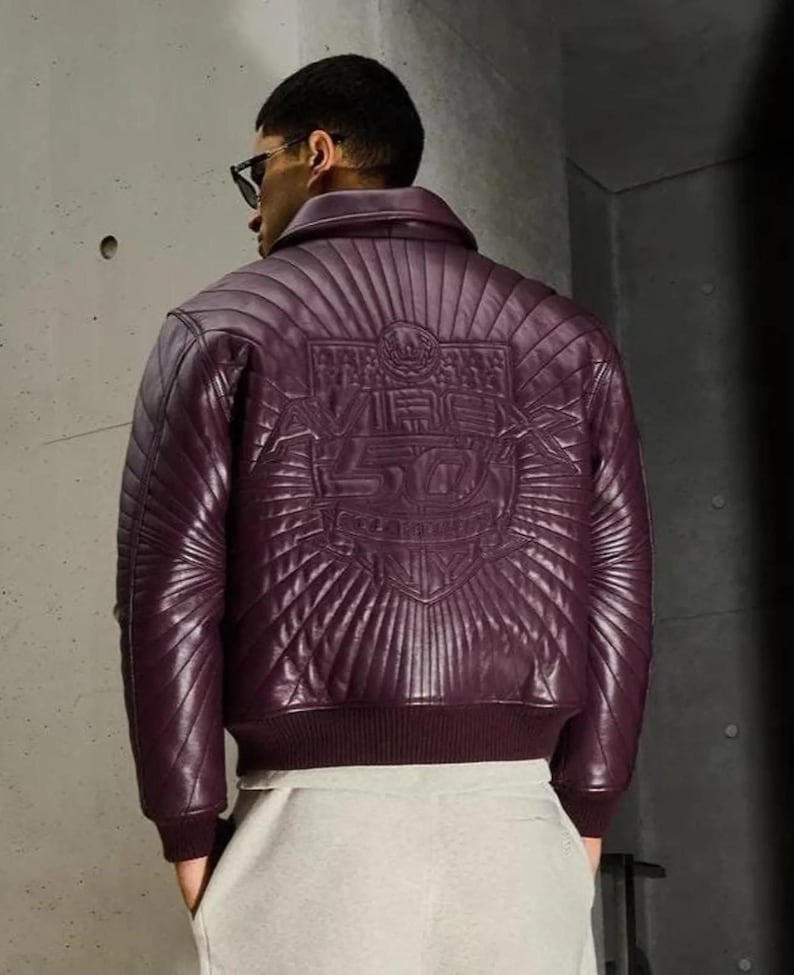 Pu&ograve; includere: Giacca bomber in pelle bordeaux con design trapuntato. La parte posteriore della giacca presenta un'emblema in rilievo con la scritta "Vibe 50". La giacca ha orlo e polsini a coste.