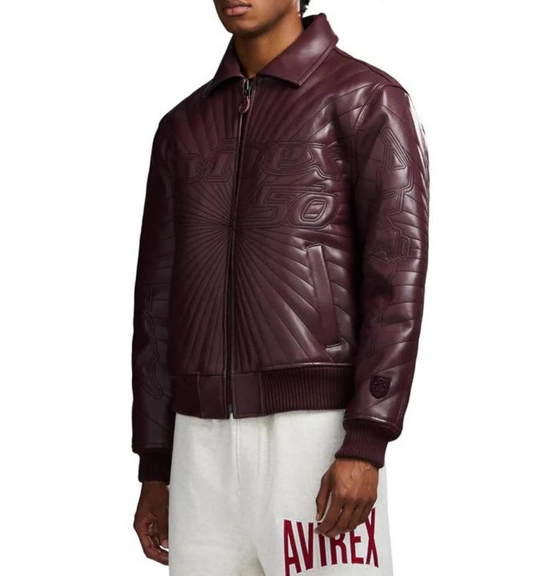 Pu&ograve; includere: Giacca in pelle bordeaux con zip, colletto e polsini e orlo a coste. La giacca presenta dettagli in rilievo sul davanti e sulle maniche, con il numero "50" in evidenza. La giacca &egrave; abbinata a pantaloni della tuta grigi.