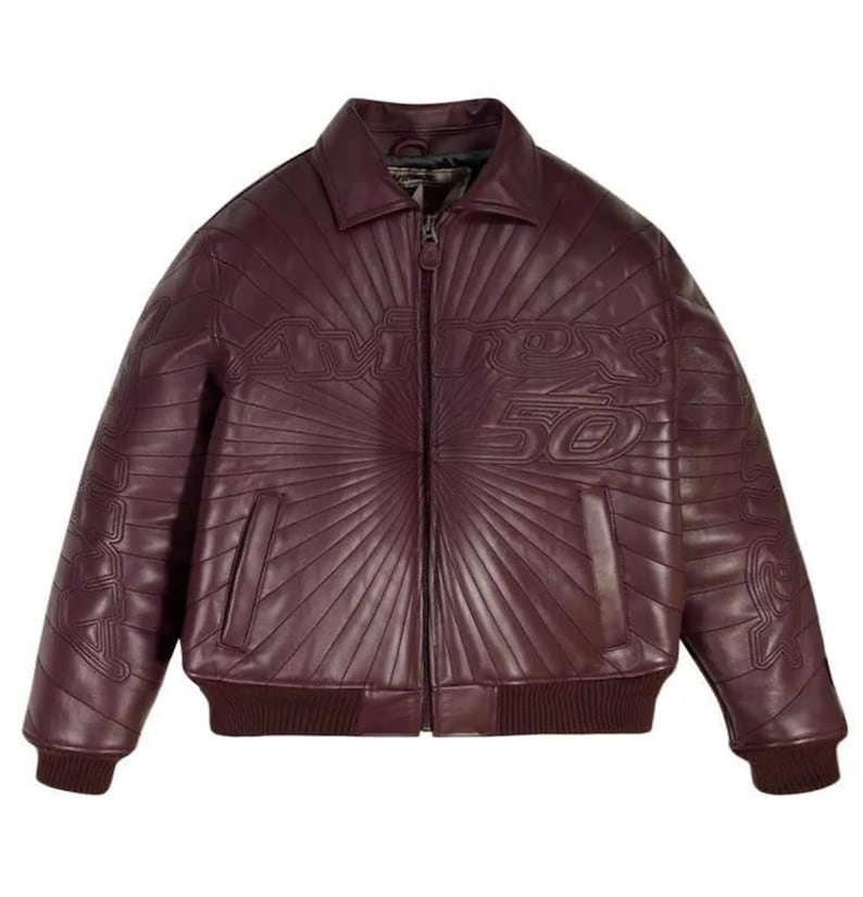 Pu&ograve; includere: Giacca in pelle bordeaux con colletto, polsini e orlo a coste. La giacca presenta una chiusura con zip frontale e due tasche anteriori. La parte anteriore della giacca presenta la scritta "AVIREX 50" in rilievo con un design radiale.