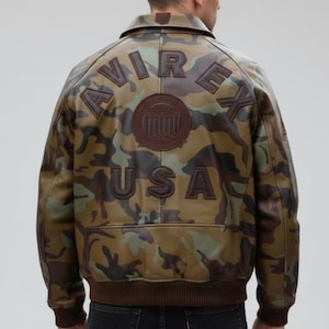 Pu&ograve; includere: Giacca in pelle con motivo mimetico con le parole "AVIREX USA" in rilievo sul retro. La giacca ha colletto, polsini e fascia in vita marroni. Il design mimetico incorpora tonalit&agrave; di verde, marrone e beige.