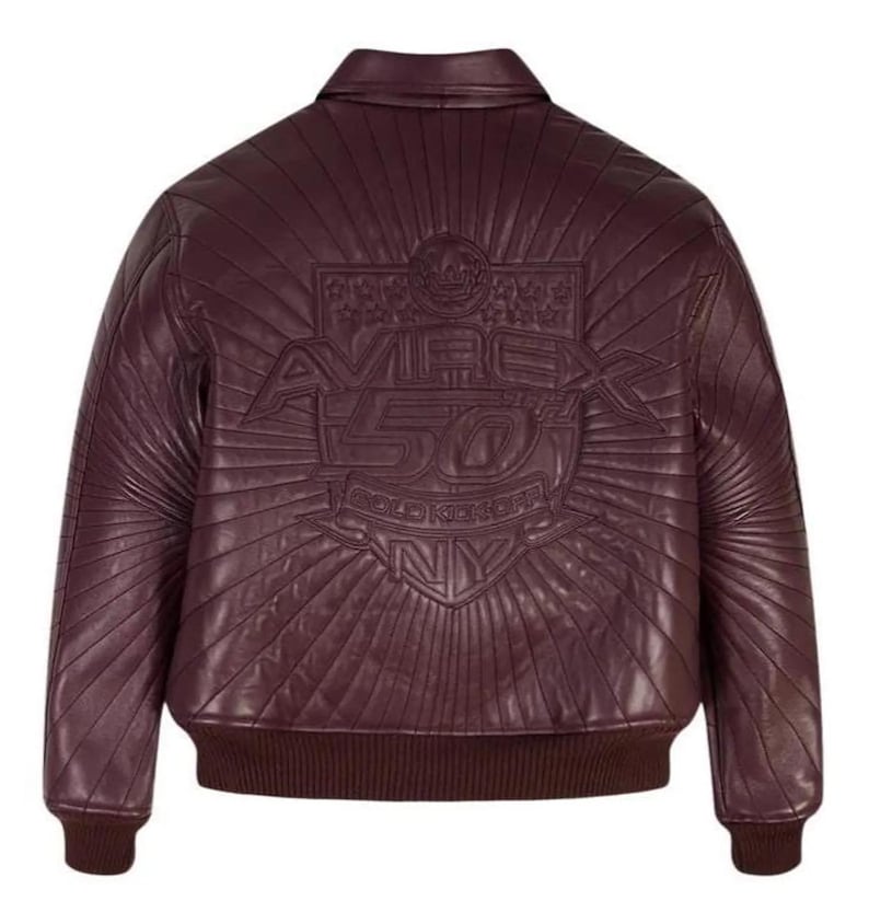 Pu&ograve; includere: Giacca bomber in pelle bordeaux con colletto, polsini e orlo a coste. La schiena presenta un design in rilievo con la scritta "AVIREX 50 GOLD KICKER NY" e un motivo a raggi solari. La giacca ha una classica silhouette bomber.