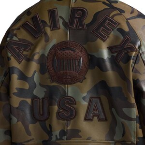 Pu&ograve; includere: Giacca in pelle con motivo mimetico con la scritta "AVIREX" sulle spalle e "USA" in basso. Una toppa circolare con "ALL AMERICAN'S" e "1975" &egrave; centrata. La giacca presenta tonalit&agrave; marroni e verdi.