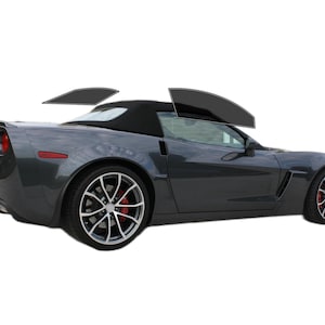 May include: A dark gray convertible sports car with black convertible top. The car has silver rims with red brake calipers. The windows are tinted. The car is on a white background.