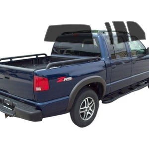 May include: A dark blue pickup truck with tinted windows and a black bed rack. The truck has the letters "Z/RS" in red on the side. The image shows the truck from a three-quarter rear view.