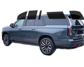 May include: A dark gray SUV with tinted windows. The vehicle has black rims and a black trim. The image shows the side and rear of the car, with the word "ESCALADE" visible on the back.