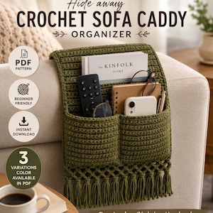 Puede incluir: Un organizador de sofá de ganchillo color verde oliva con dos bolsillos y un borde inferior con flecos. El organizador contiene un libro titulado The Kinfolk Home, un mando, un cuaderno, un smartphone y un bolígrafo. El texto dice Hide away CROCHET SOFA CADDY.